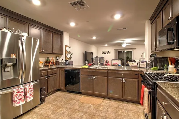 a kitchen with stainless steel appliances granite countertop a sink a stove a refrigerator cabinets and a refrigerator