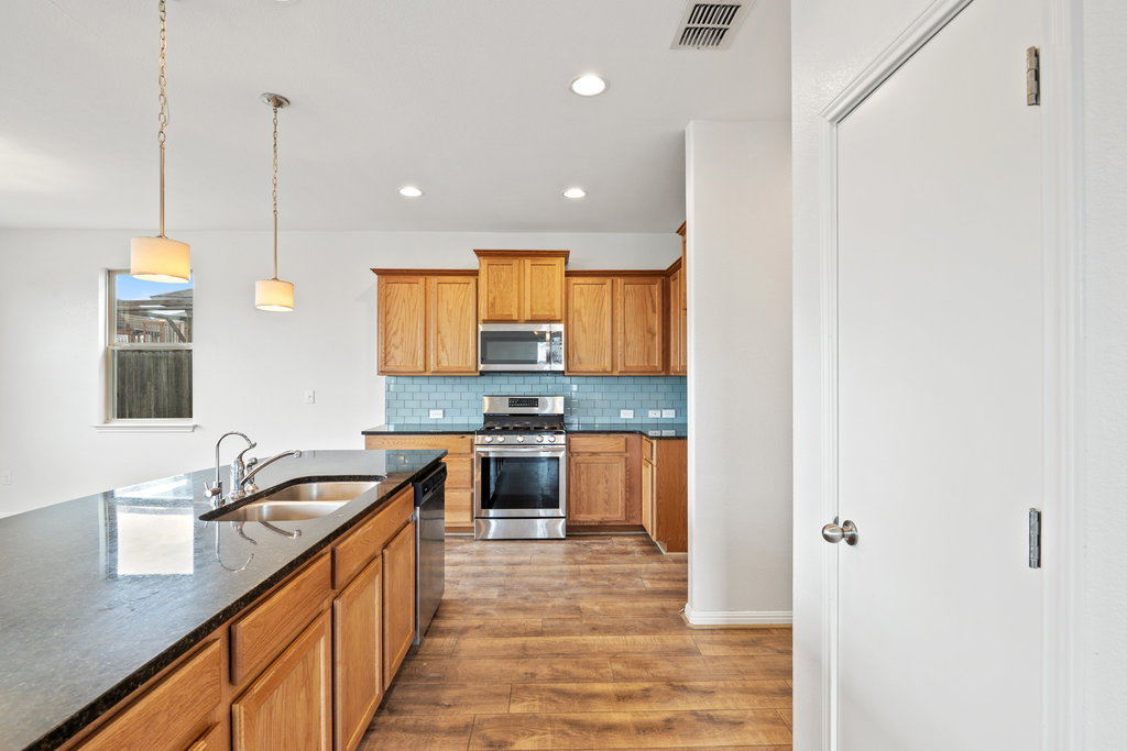 117 Wapiti Road Buda, TX 78610 - Photo 11 of 35 a kitchen with stainless steel appliances granite countertop a sink a stove and a refrigerator