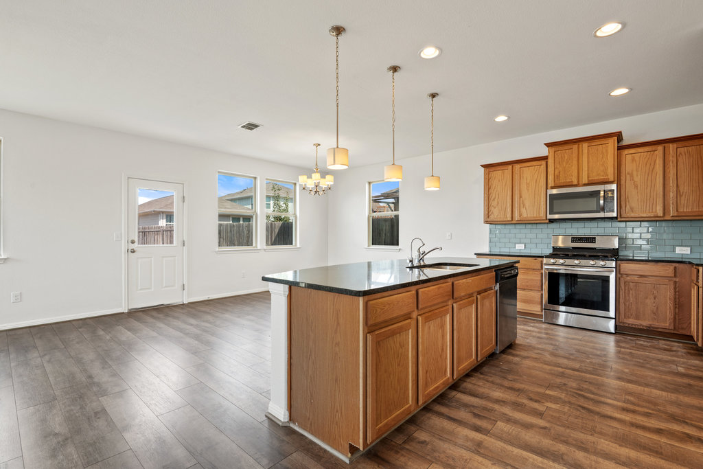 117 Wapiti Road Buda, TX 78610 - Photo 13 of 35 a kitchen with stainless steel appliances granite countertop a sink a stove and a wooden floors