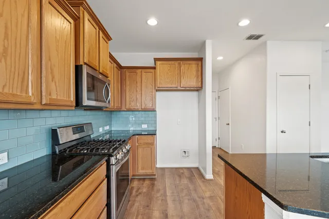 a kitchen with stainless steel appliances granite countertop a stove a sink and a refrigerator
