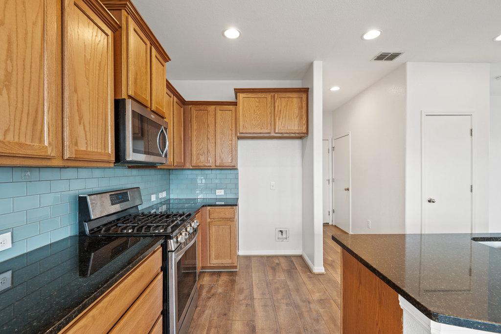 117 Wapiti Road Buda, TX 78610 - Photo 10 of 35 a kitchen with stainless steel appliances granite countertop a stove a sink and a refrigerator