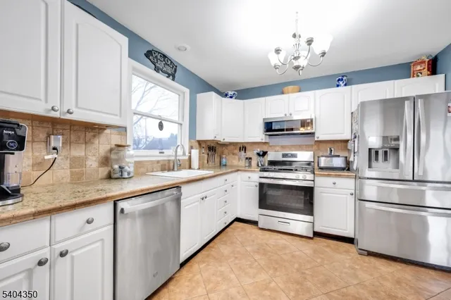 a kitchen with granite countertop white cabinets and stainless steel appliances