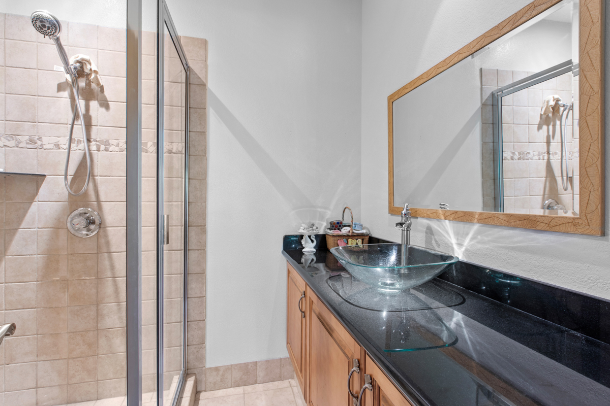 73-4571 Kukuki Street, Unit A Kailua-Kona, HI 96740 - Photo 16 of 30 a bathroom with a granite countertop sink a mirror and shower