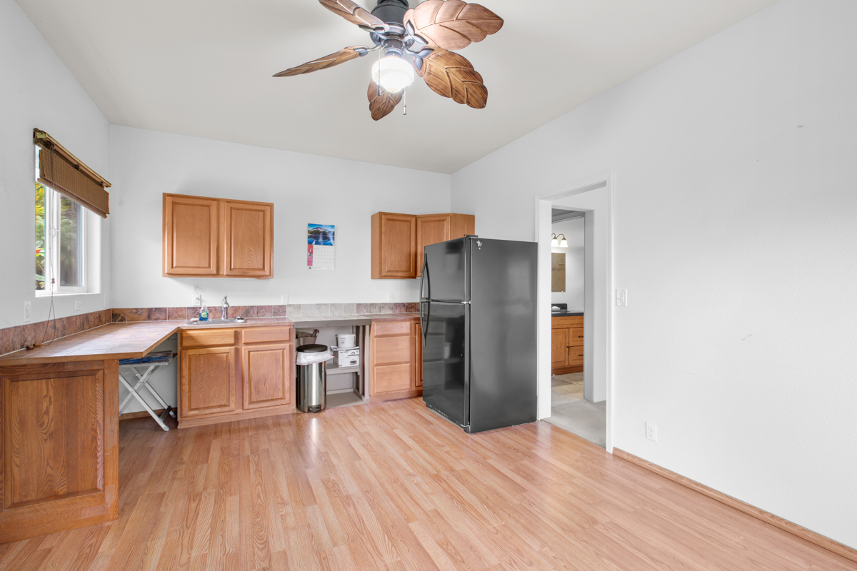 73-4571 Kukuki Street, Unit A Kailua-Kona, HI 96740 - Photo 23 of 30 a kitchen with stainless steel appliances a refrigerator and wooden floor