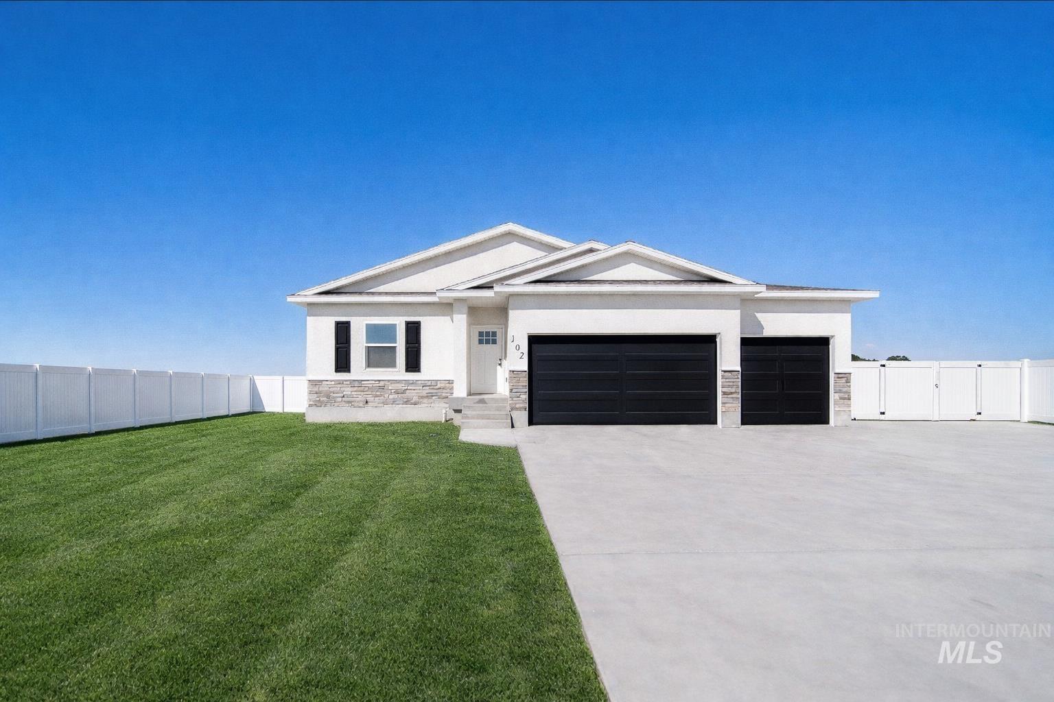 102 North Stocktrail Drive Rigby, ID 83442 - Photo 1 of 1 View of front of home featuring stone siding, an attached garage, concrete driveway, stucco siding, and a gate