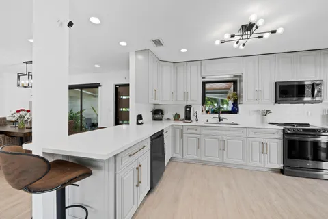 a kitchen with stainless steel appliances granite countertop a sink a stove and cabinets