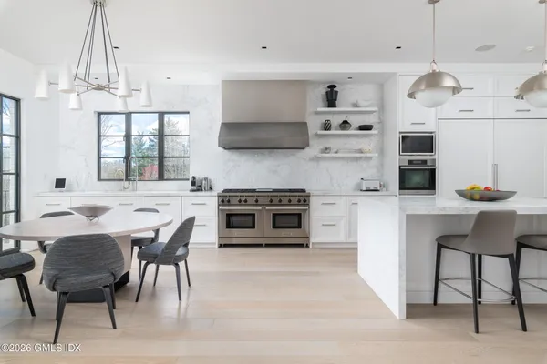 a kitchen with stainless steel appliances a dining table chairs and a large window