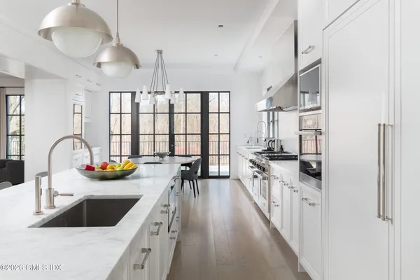 a large white kitchen with lots of counter space and a chandelier