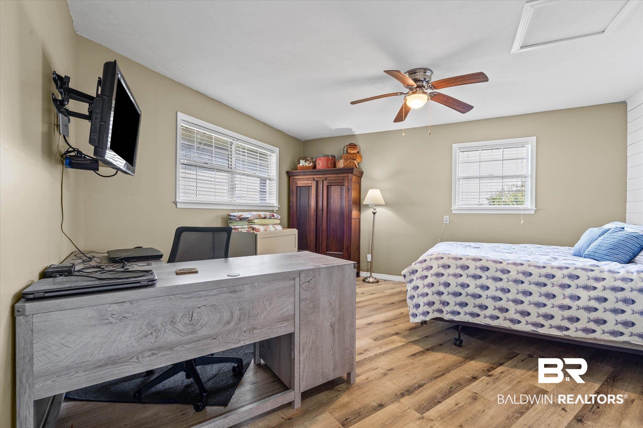 9100 Shell Belt Road Coden, AL 36523 - Photo 15 of 38 Room featuring wood-finish flooring, two windows with blinds, a ceiling fan with integrated lighting, and a wall-mounted television bracket