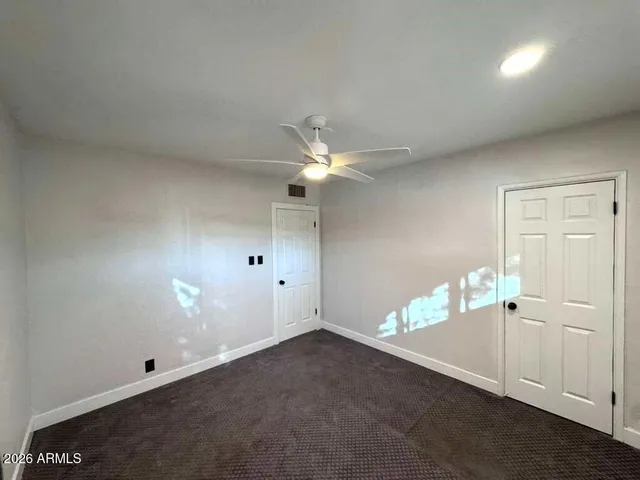 an empty room with a ceiling fan and window