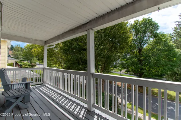 a view of a room with wooden floor next to a iron stairs