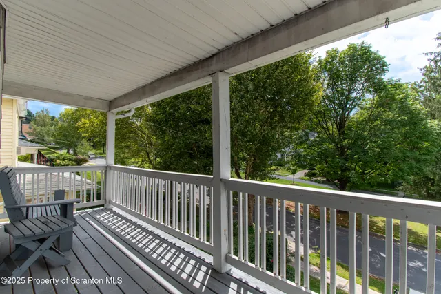 a view of a room with wooden floor next to a iron stairs