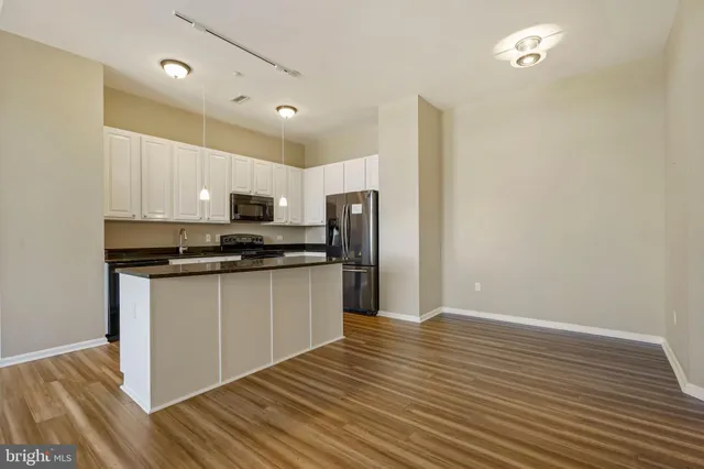 a kitchen with granite countertop a refrigerator and a stove top oven