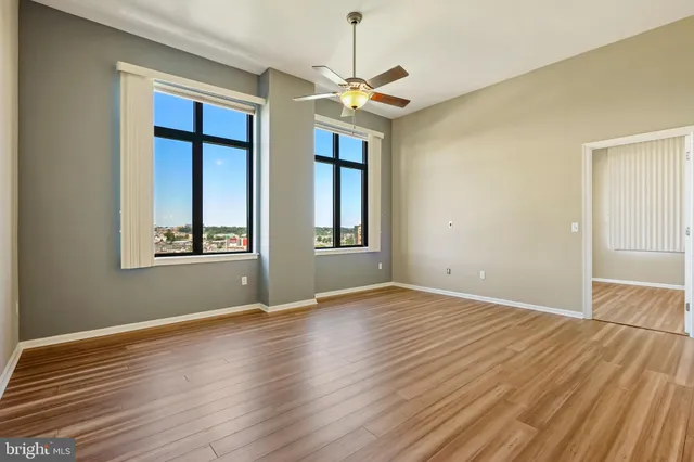 a view of an empty room with window and wooden floor