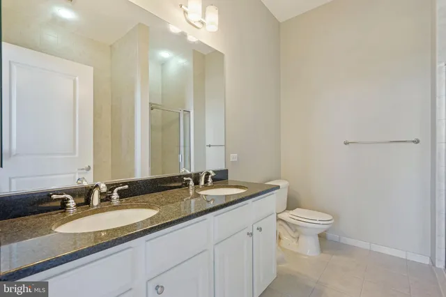 a bathroom with a granite countertop sink a toilet and a mirror