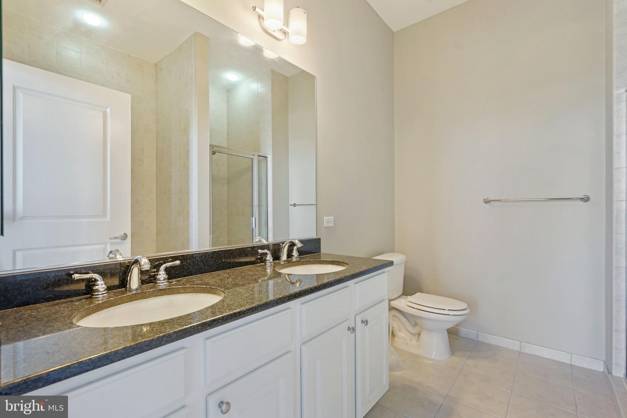2720 South Arlington Mill Drive, Unit 1102 Arlington, VA 22206 - Photo 21 of 28 a bathroom with a granite countertop sink a toilet and a mirror