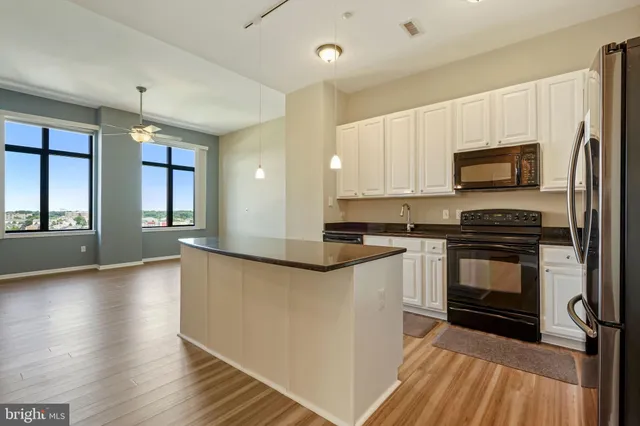 a kitchen with granite countertop a stove top oven a sink dishwasher and a refrigerator with wooden floor