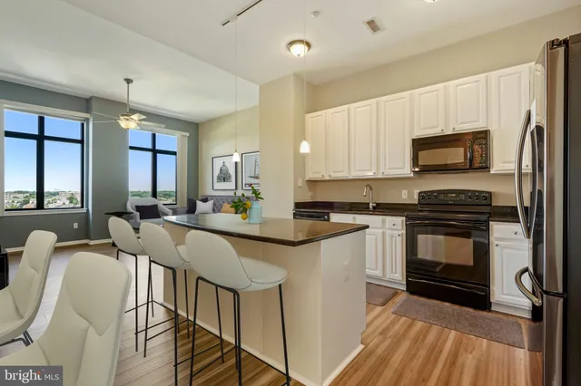 a kitchen with stainless steel appliances a stove a sink dishwasher a refrigerator white cabinets and wooden floor next to a window