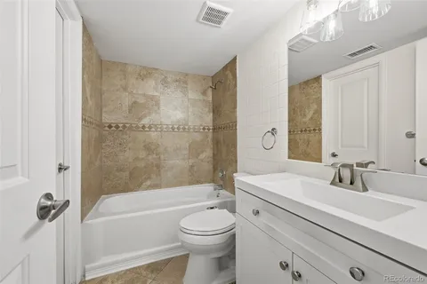 a bathroom with a bathtub shower sink vanity mirror and toilet