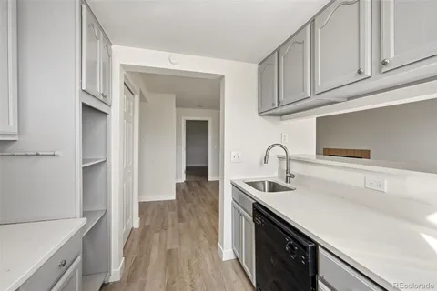 a kitchen with stainless steel appliances granite countertop a sink dishwasher stove and white cabinets with wooden floor