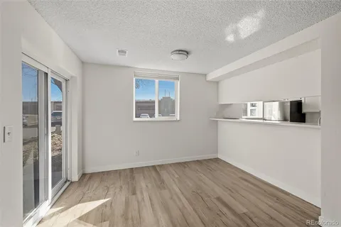 a view of kitchen and empty room with wooden floor