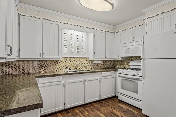 a kitchen with granite countertop white cabinets and white appliances
