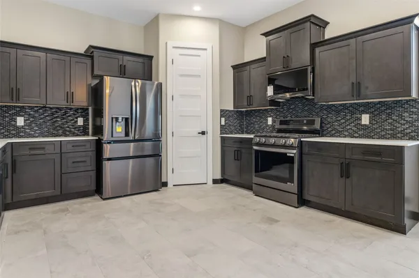 a kitchen with stainless steel appliances granite countertop a stove a refrigerator and a sink with wooden cabinets