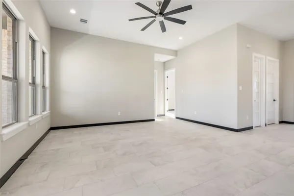 an empty room with fireplace and chandelier fan