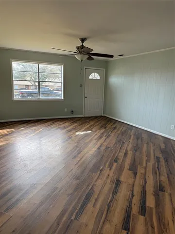 an empty room with wooden floor ceiling fan and windows
