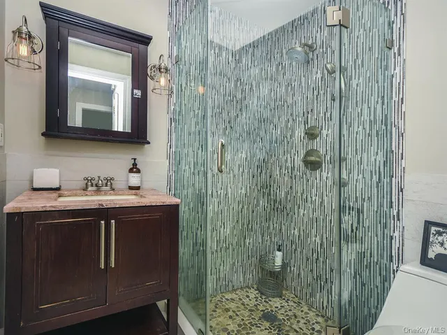 a bathroom with a granite countertop sink a mirror and shower