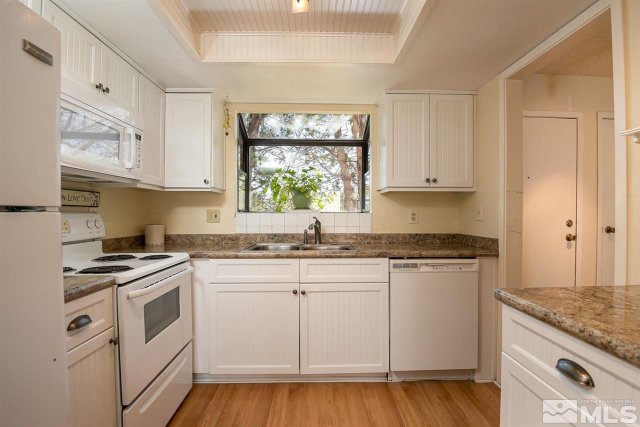 1235 Conway Lane Reno, NV 89503 - Photo 13 of 37 a kitchen with granite countertop white cabinets and white appliances