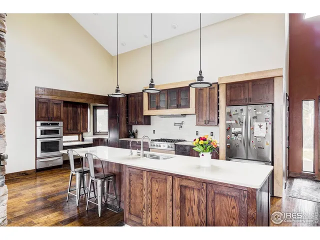 a kitchen with stainless steel appliances kitchen island granite countertop a refrigerator a sink a stove and a refrigerator