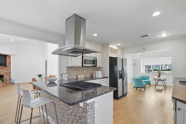 a kitchen with stainless steel appliances granite countertop a stove refrigerator and chairs