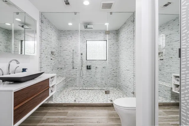 a bathroom with a sink a toilet a mirror and shower