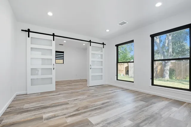 a view of an empty room with a window and wooden floor