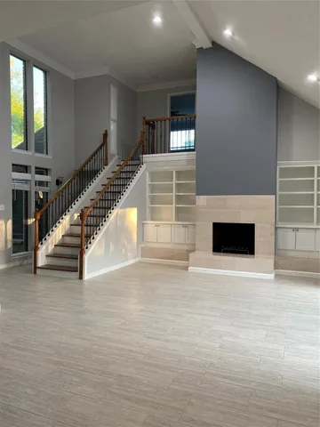 a view of an empty room with wooden floor and a fireplace