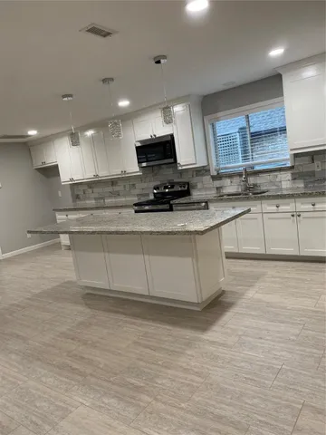 a kitchen with stainless steel appliances granite countertop a sink a stove and a granite counter top