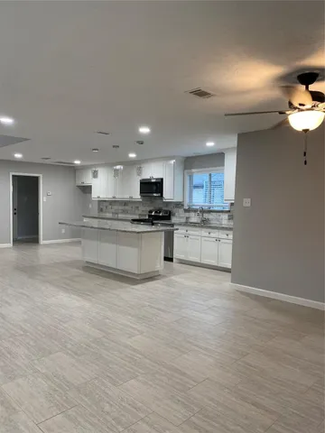 a large kitchen with stainless steel appliances granite countertop a stove a sink and a microwave