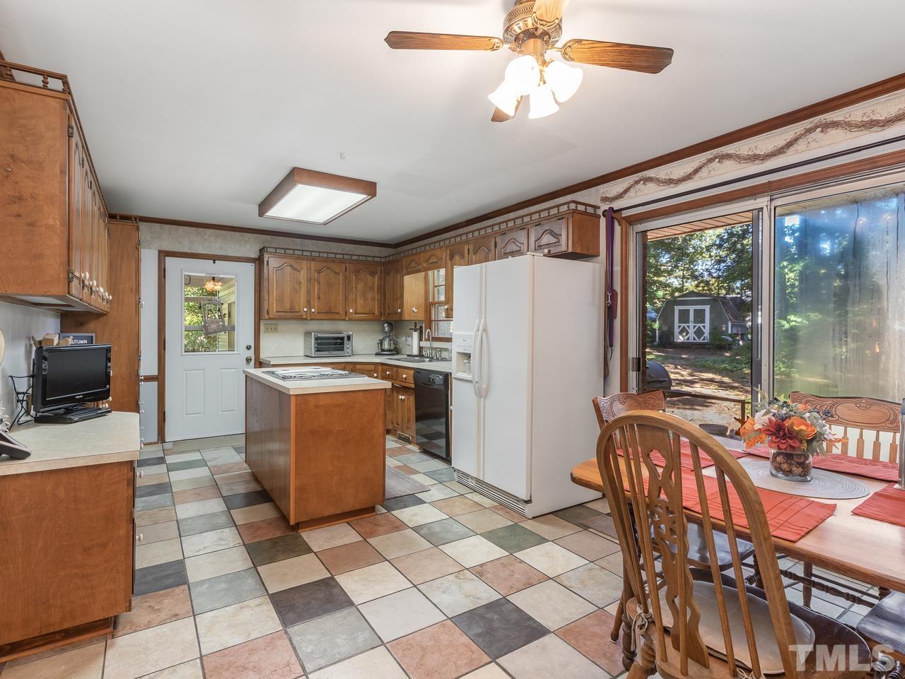3205 Fairforest Place Raleigh, NC 27604 - Photo 10 of 28 a kitchen with stainless steel appliances granite countertop a stove a refrigerator a kitchen island a dining table and chairs with the wooden floor