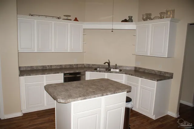 a kitchen with granite countertop a sink a stove and cabinets