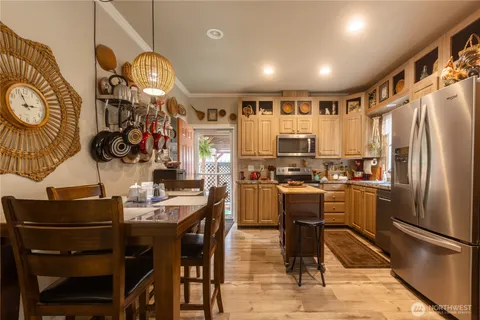 a kitchen with stainless steel appliances kitchen island granite countertop a refrigerator a stove a oven with white cabinets and wooden floor