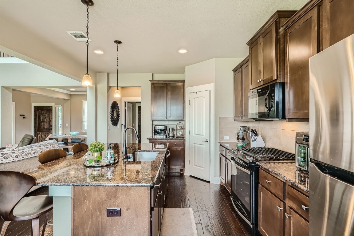 9401 McKnight Loop, Unit 6 Austin, TX 78717 - Photo 10 of 28 a kitchen with stainless steel appliances kitchen island granite countertop a sink refrigerator and cabinets