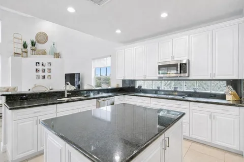 a kitchen with stainless steel appliances kitchen island granite countertop a table and chairs