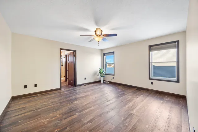an empty room with wooden floor and chandelier fan