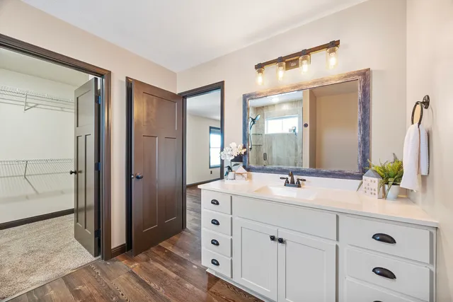 a spacious bathroom with double vanity a mirror and a shower