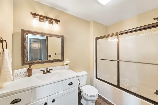 a bathroom with a sink a toilet a mirror and shower