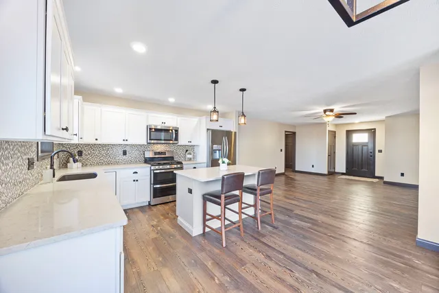 a kitchen with stainless steel appliances a dining table chairs stove and cabinets