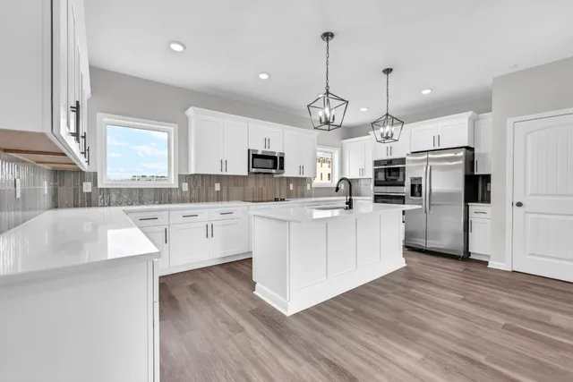 a large kitchen with cabinets a sink a counter space stainless steel appliances and cabinets