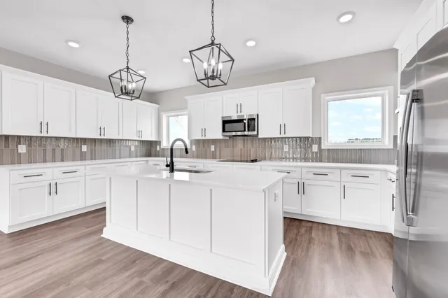 a kitchen with a refrigerator a white cabinets and wooden floor