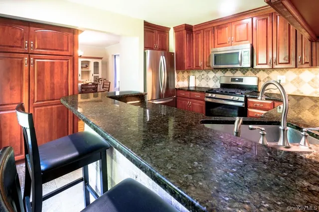 a kitchen with stainless steel appliances granite countertop a sink refrigerator and microwave